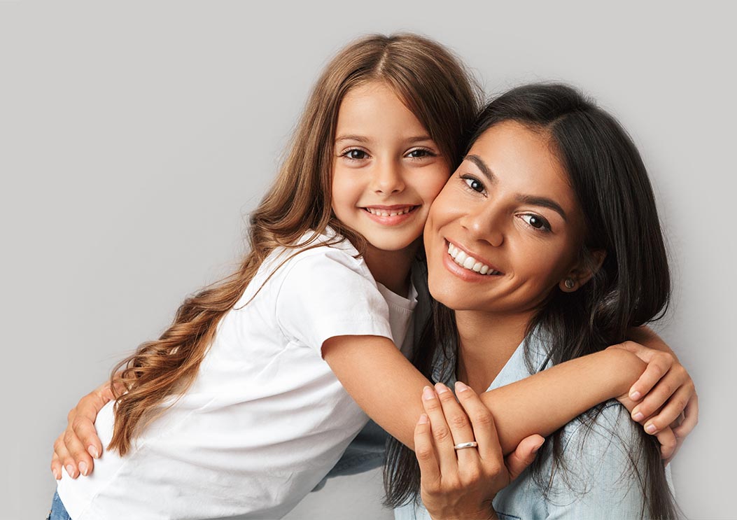 Photo of attractive woman with little daughter smiling and hugging together isolated over gray background